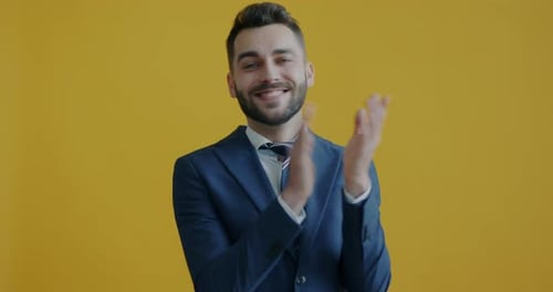 Portrait of Happy Businessman Clapping Hands and Shouting Bravo Looking at Camera on Yellow