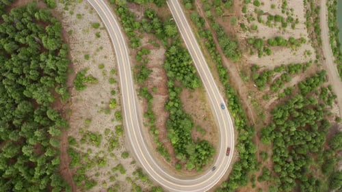 Long Winding U-Shaped Road Slow Aerial Rotational Ascent - Moving Traffic Mountain Forest View 4K