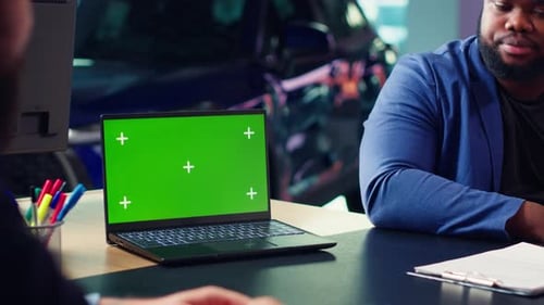 Two People at Desk With Laptop and Green Screen