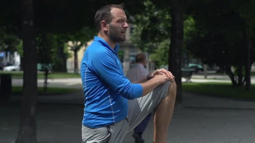 Young, Sporty Man Stretching Legs on Bench in City Park, Super Slow