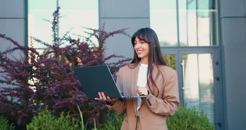 Woman in Suit Video Calling on Laptop Outdoors