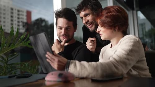 Happy friends holding tablet smiling and laughing looking at video content online