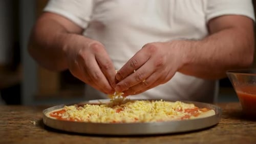 Professioneller Koch bereitet Pizza mit Mozzarella und Tomatensauce zu