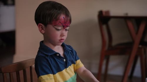 Boy With Face Paint Playing at Table Indoors