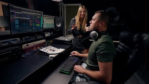 a girl singer and a male sound engineer work together in recording studio to create a new song