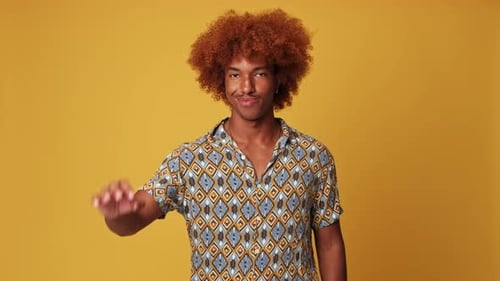 Happy guy puts his fingers in an ok gesture isolated on yellow background in studio