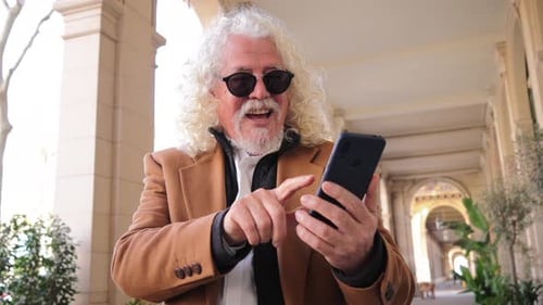 Smiling man with sunglasses using smartphone outdoors