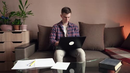 A young man works from home on a computer. quarantine, isolation. cozy room
