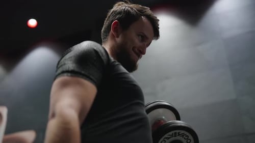 Male sportsman do standing dumbbell biceps curl at indoor gym facility