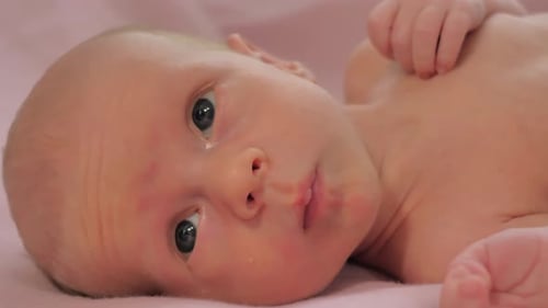 Closeup of Face of Newborn Baby Caucasian Child Laying on the Bed and Looking Around Slow Motion
