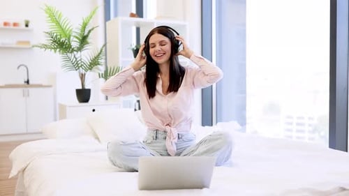 Woman Enjoying Music on Laptop in Bright Home