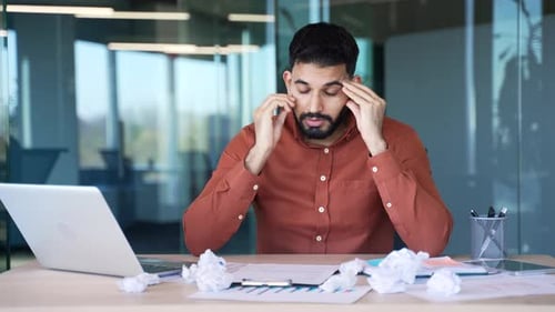 Exhausted businessman is bored sitting at workplace at desk in business office. Overworked