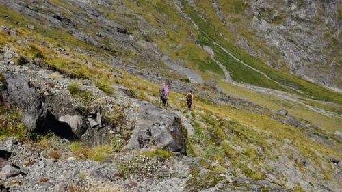 Panoramaaufnahme eines Wanderpaares, das an sonnigen Tagen bei Gertrude Saddl steile grüne Berge bergab wandert