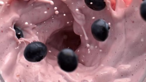 Blueberries Being Added to Pink Smoothie in Blender