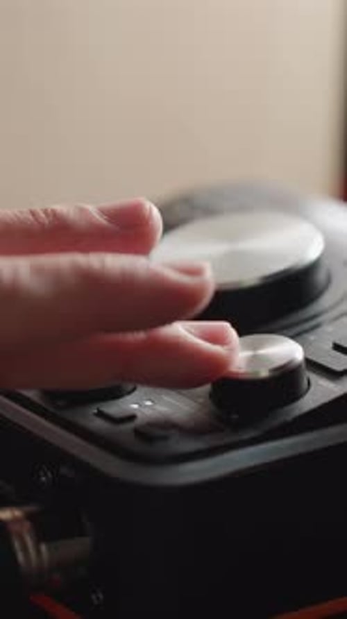 CloseUp of Hand Adjusting Sound Mixer Knobs for FineTuning Audio Levels