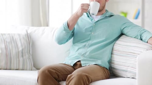 Man Relaxes on Couch Enjoying a Hot Drink