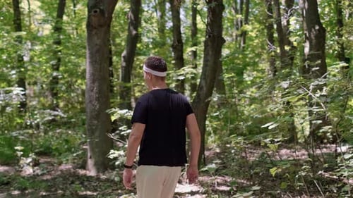 Running training program in a forest setting. A man runs in the park, smiles at the camera, enjoying