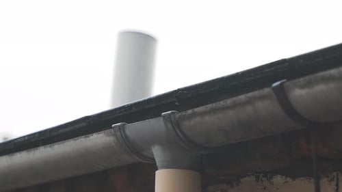 Gros plan de la pluie tombant sur le toit dans une gouttière - 4K