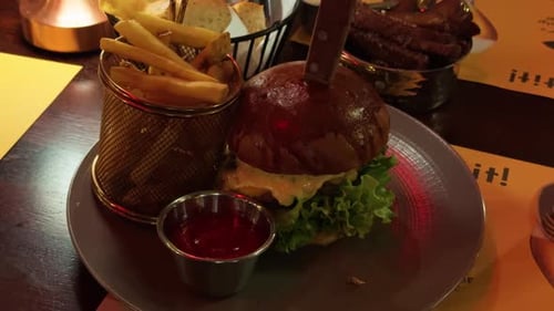 Una hamburguesa deliciosamente jugosa servida con patatas fritas crujientes y sabrosa salsa para mojar en un acogedor restaurante