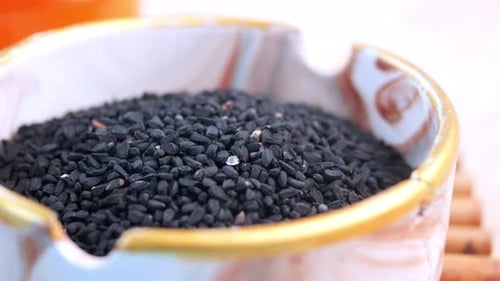 Semillas negras y su aceite bellamente dispuestas en un tazón rústico de madera para usos culinarios
