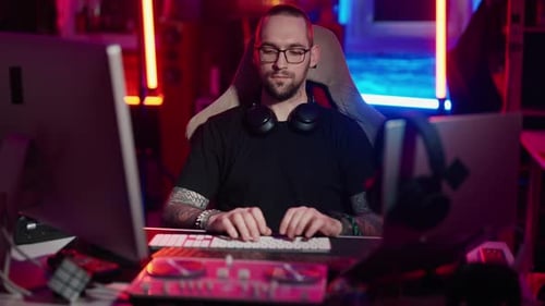 Man Working at Computer in Neon Lit Room
