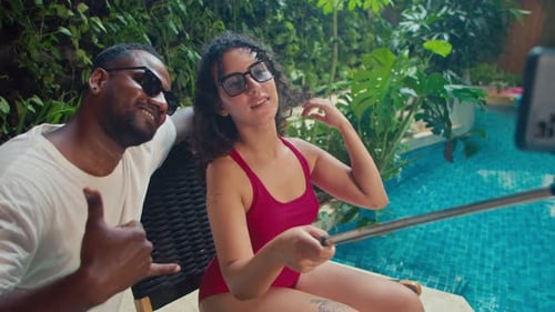 Happy Couple Using Smartphone with Selfie Stick at Hotel Pool