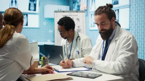 Doctors Meeting and Reviewing Medical Charts in Office