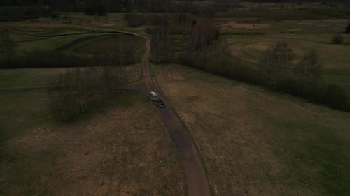 Aerial View of Car on Dirt Road Through Grassy Landscape