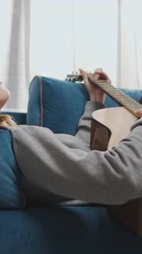 Woman Lying on Sofa Playing Acoustic Guitar