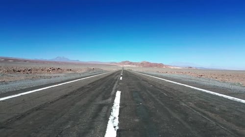 Rápido vuelo a baja altura que se desliza por encima de una carretera pavimentada del desierto que se extiende sin cesar a través de zonas áridas