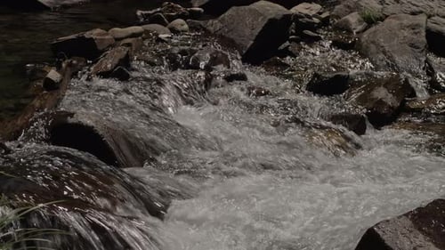 Flowing stream water over rocks and stones