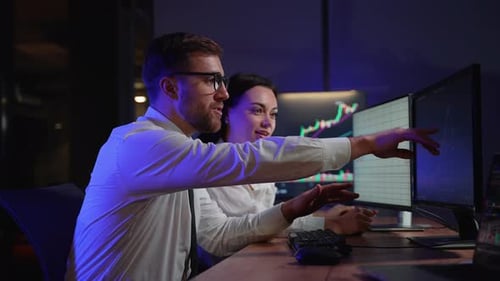 Excited Colleagues High Five at Nighttime Workplace