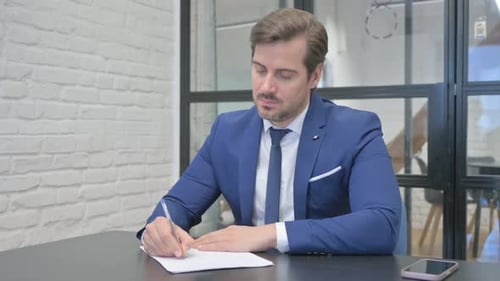Mature Adult Businessman Writing a Letter in Office