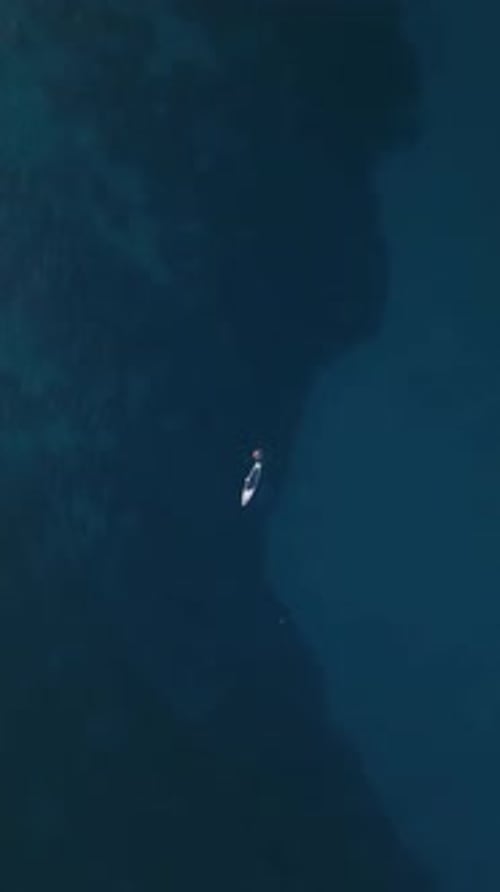 Vertical Video Aerial View of a Paddle Board a Man is Sailing on the Blue Sea