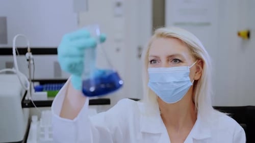 Woman Scientist Analyzing Blue Liquid in Laboratory
