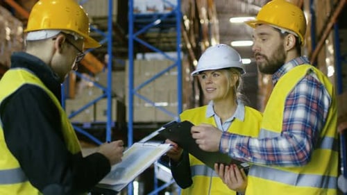 Team of Male and Female Inspectors/ Workers/Auditors Have Discussion in Big Warehouse with Rows of