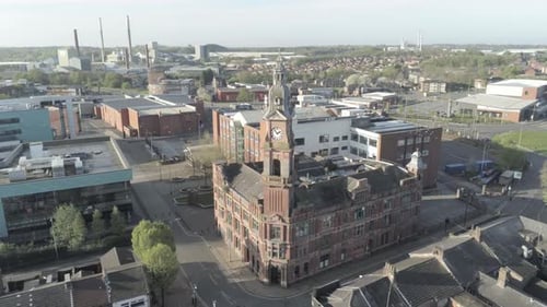 Deserted UK small town college campus buildings and clock tower aerial slow orbit pull back right vi