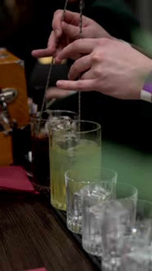 Bartender stirs cocktail at bar in close up