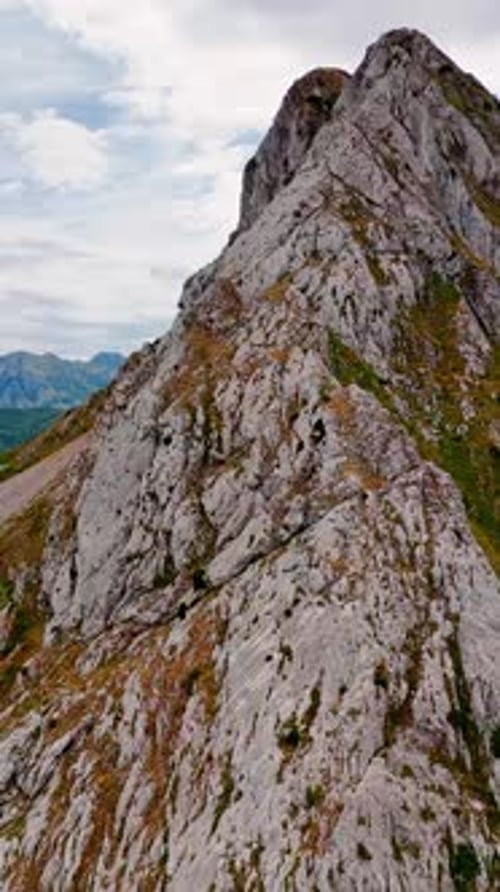 Footage close at the huge grey rock with some lichens growing on. Green rocky landscape at backdrop