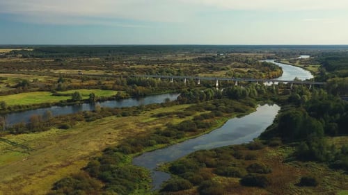 A Serene and Picturesque River Landscape Embraced By Lush Greenery and Expansive Open Fields