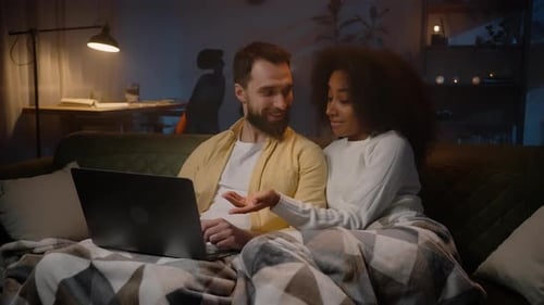 Couple Using Laptop Together Under Blanket on Couch