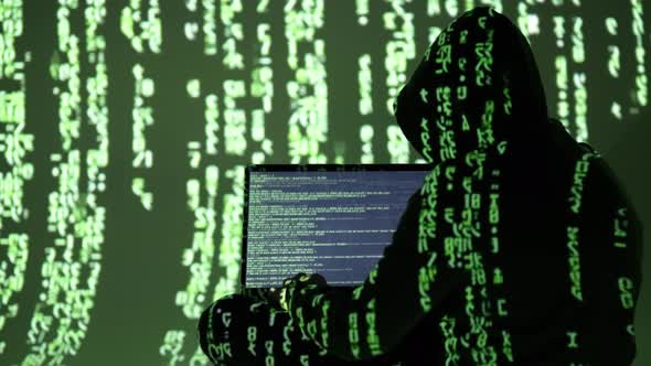 Hacker in Hoodie Working on Laptop Fully Covered in Matrix Code with ...