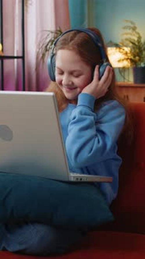 Smiling Girl Using Laptop with Headphones at Home