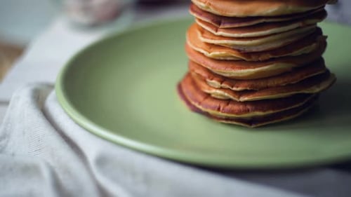 Panning on delicious american pancakes stacked high on a green plate