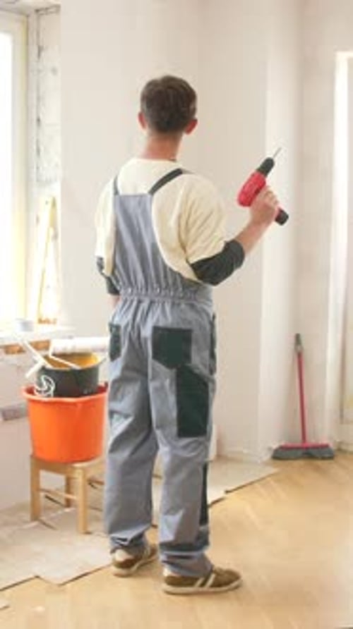 Young Adult Holding Drill in Unfinished Room
