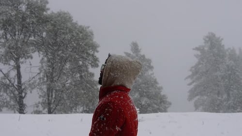 30-03-24; A man in a jacket enjoys the snowfall amidst hill covered with snow.