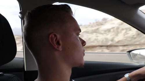 Seitenansicht eines jungen Mannes, der beim Autofahren direkt auf die Straße schaut