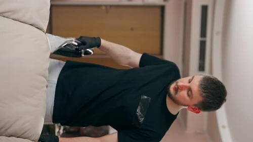 Young Adult Cleans Sofa with Cleaning Machine