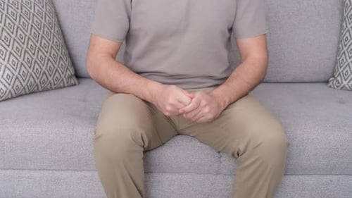 Man Sitting on Couch Clasped Hands Waist Shot