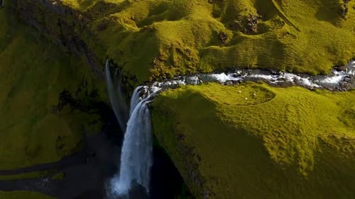 Drone View of Magnificent Waterfall Tumbling Over Vibrant Green Mossy Cliffs